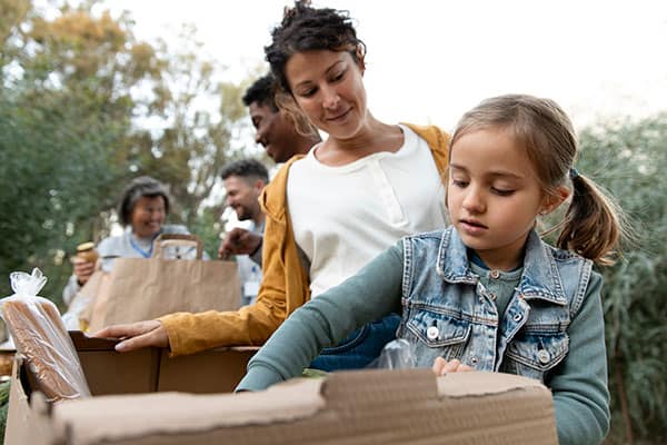 volunteers placing items in box include a young girl